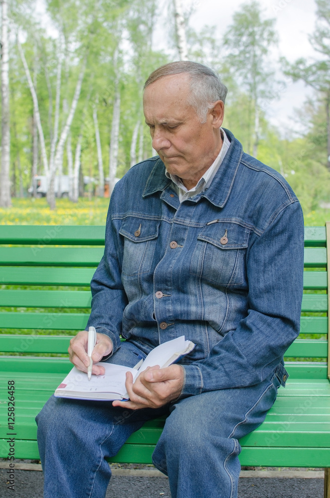Fototapeta premium Aged man is making notes in the daily planner