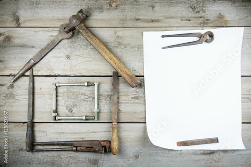 The concept of a house under construction. Old wooden desktop. Old rusty carpentry tools. Horizontal mockup