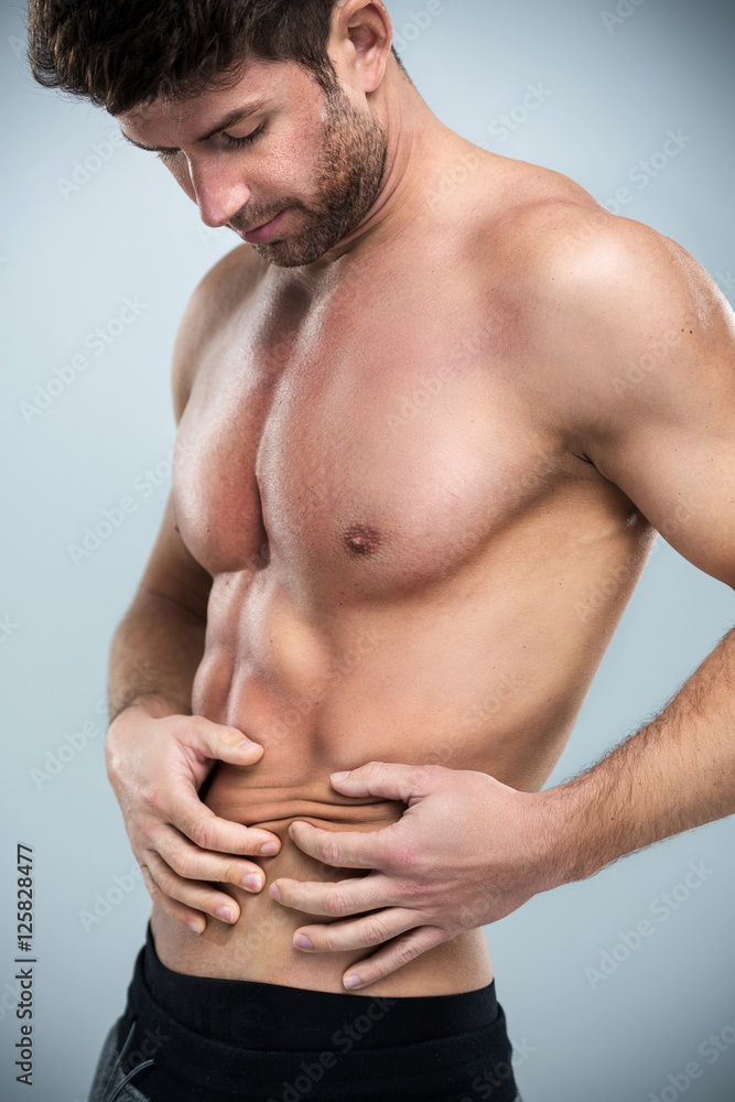 Fototapeta premium Muscular man pinching a fat on his abdomen 