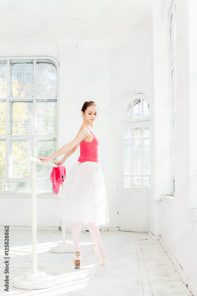 Ballerina posing in pointe shoes at white wooden pavilion Ballerina posing in pointe shoes at white wooden pavilion
