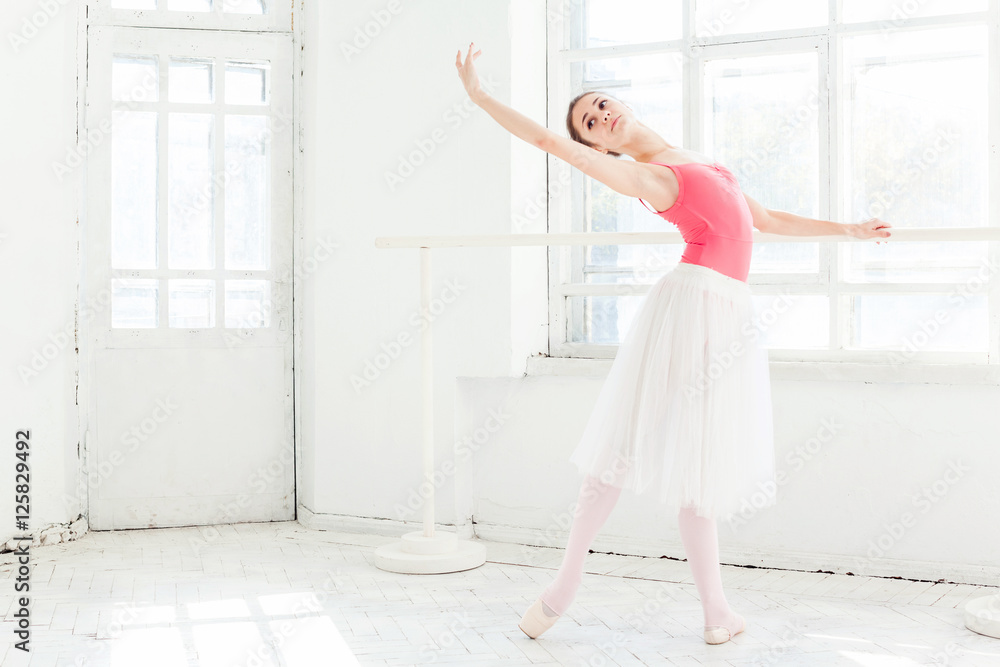 Ballerina posing in pointe shoes at white wooden pavilion Ballerina posing in pointe shoes at white wooden pavilion