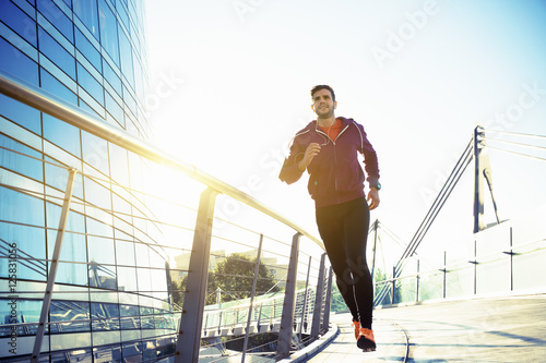 athlete with earphones running in the city