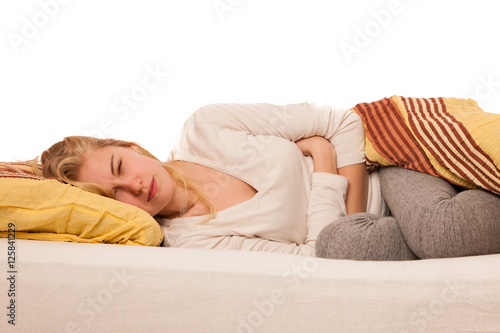 Woman lying in bed holding belly because of the pain in stomac.