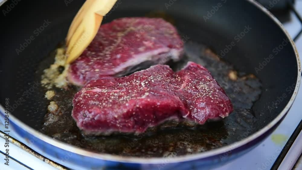 Beef ribeye steak being fried in a pan on the stove Beef ribeye steak being fried in a pan on the stove