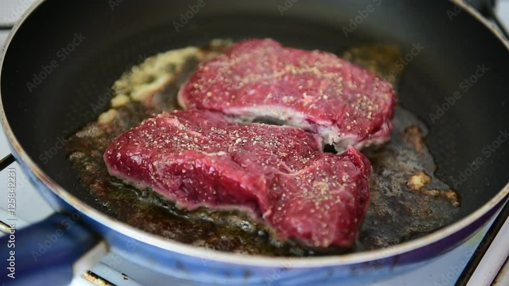 Beef ribeye steak being fried in a pan on the stove Beef ribeye steak being fried in a pan on the stove
