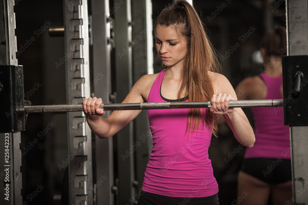 Woman workout in fitness gym with barbells - powerlift workout Woman workout in fitness gym with barbells - powerlift workout