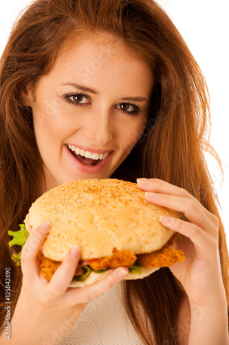 Unhealthy meal - happy young woman eats hamburger isolated over
