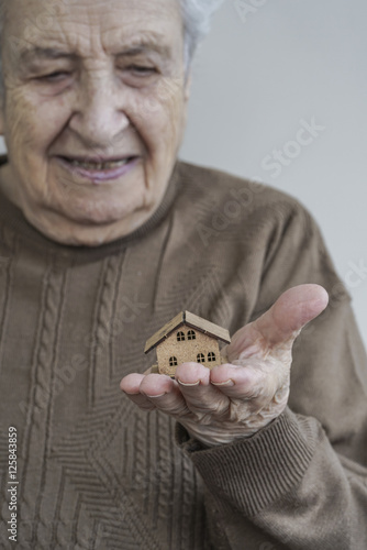 senior woman holding a small wooden house