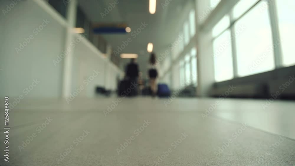 two people going with suitcase in modern airport terminal. Business travel people out of focus and blurry in background. two people going with suitcase in modern airport terminal. Business travel people out of focus and blurry in background.