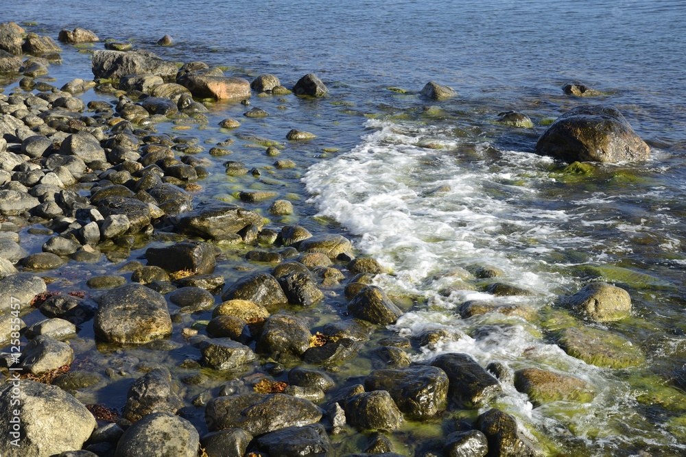 Waves on stone beach, waters edge abstract sea background.