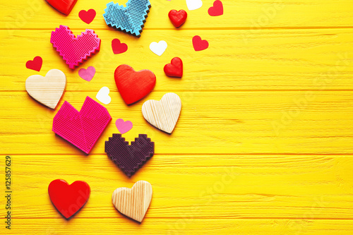Colorful hearts on yellow wooden background