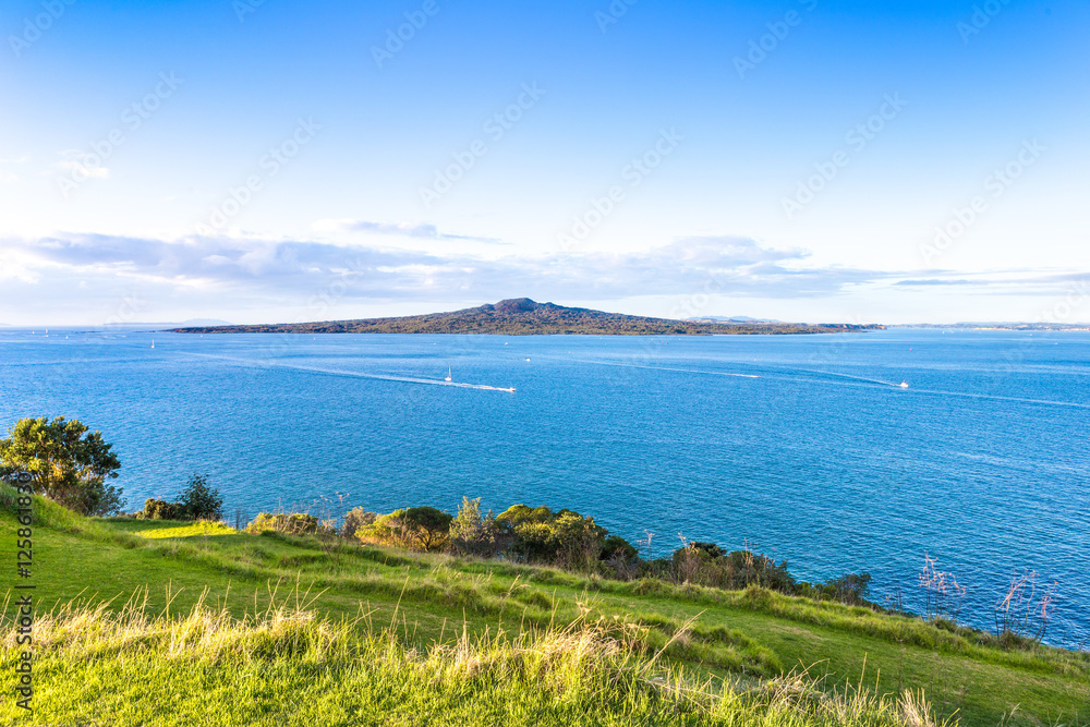 Sunset pacific landscape with a volcano on a horizon. Rangitoto island in Hauraki gulf, view from Devonport, Auckland. New Zealand