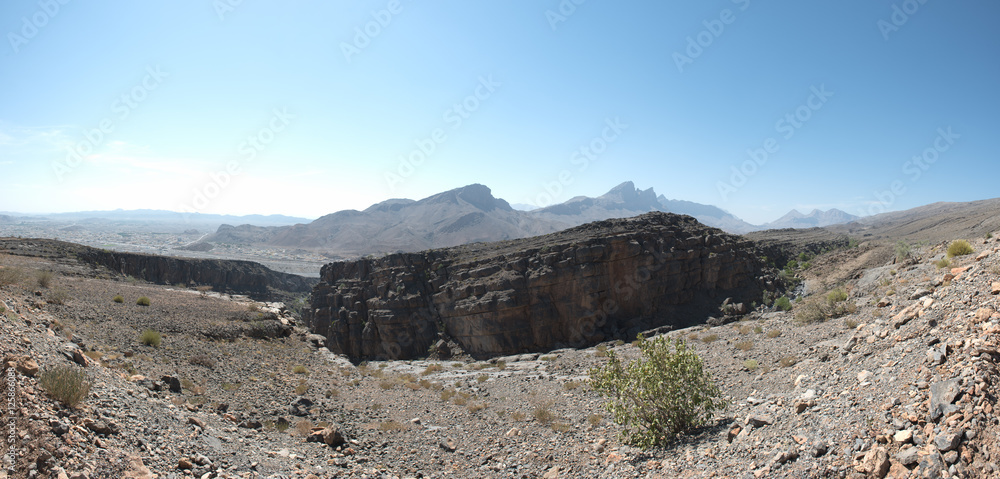 An arid mountainous landscape under a cloudless blue sky