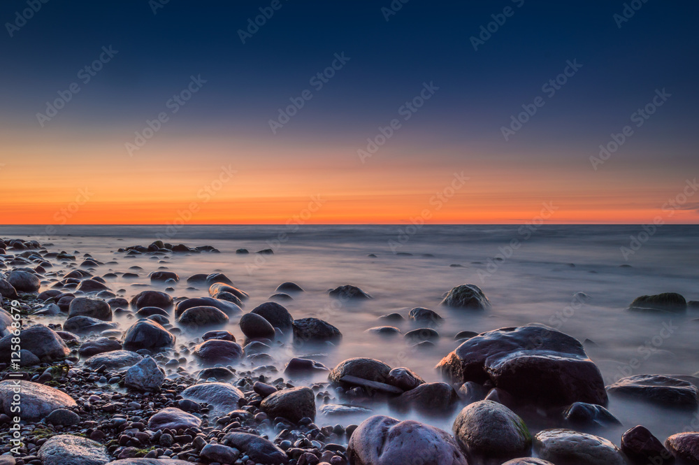 Obraz premium Sunset over the sea. Stone on the foreground.