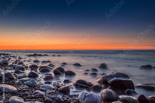Sunset over the sea. Stone on the foreground. © Kazick