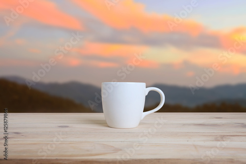 Cup of coffee on a wooden table and nature background.