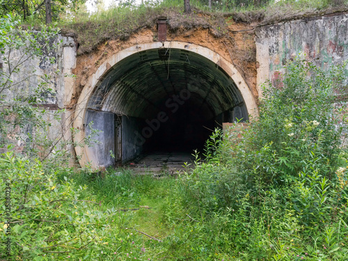 Old abandoned undetected military undeground tunnel storage among wild tall weeds. Kaluzhskaya region, Russia. 