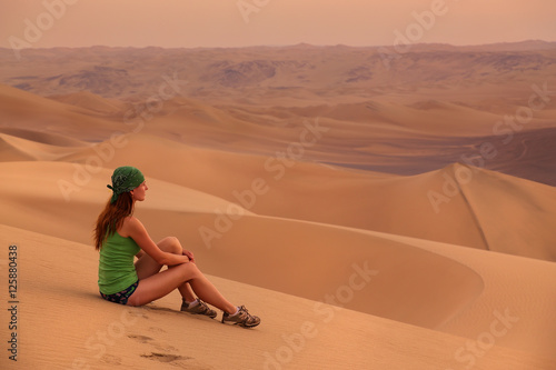 Young woman sitting on sand in a desert near Huacachina, Ica reg