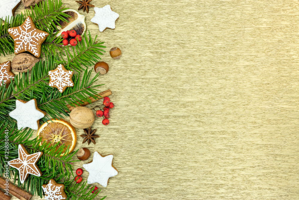 gingerbread christmas decorations with green fir-tree branches on golden background gingerbread christmas decorations with green fir-tree branches on golden background