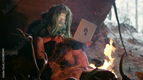 Prehistoric caveman using laptop photo