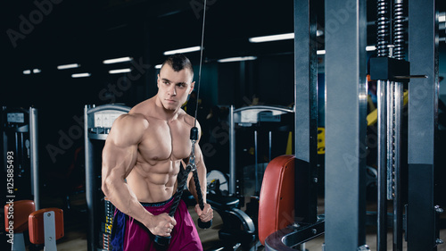 Male bodybuilder, fitness model trains in the gym