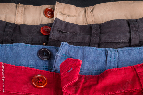 Fotografi Fragment of four cotton twill pants red, blue, black, beige with open buttons