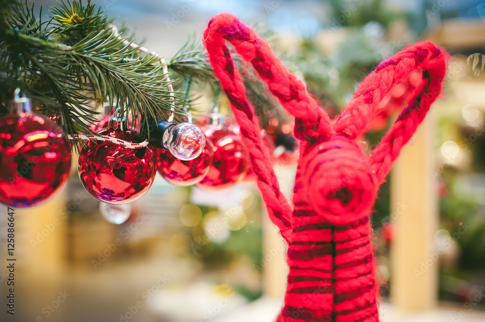Christmas decorative red balls hanging on a green branches blurry bokeh on threads, decorated with fir branches