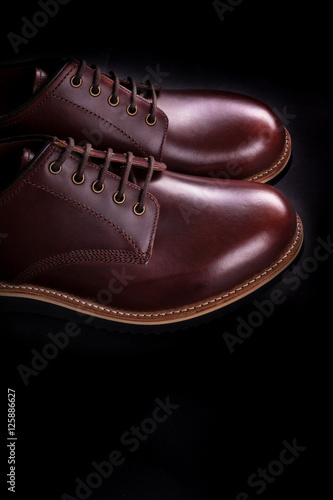 Brown oxford shoes on black background. Back view. Copy space.