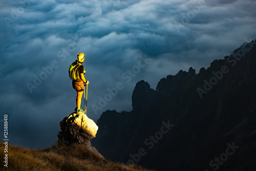 Foto Fantastic sunset in mountains with hiker on a stone where he arr