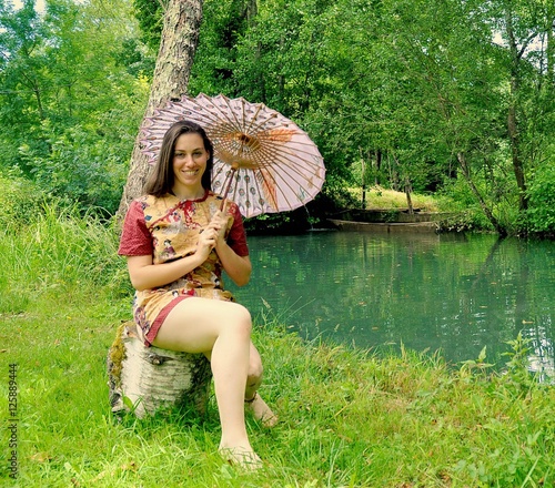 Jeune femme avec un parassol  au bord de l'eau photo