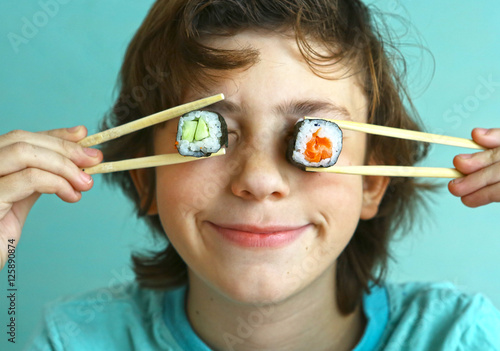 preteen handsome boy with sushi roll set photo