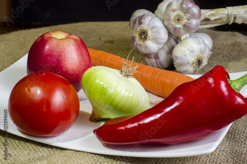 warzywa, papryka, czosnek, pomidor i jabłko na białej tacy i płótnie