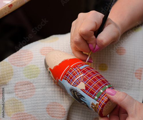 The artist draws a doll-matryoshka. Hand closeup