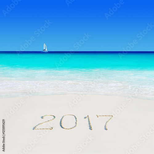Yacht under sail at beach and year 2017 sand caption