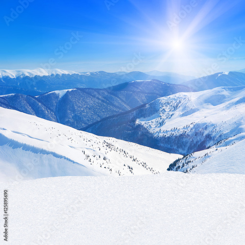 Winter snowy mountains peaks landscape against blue sunny sky background