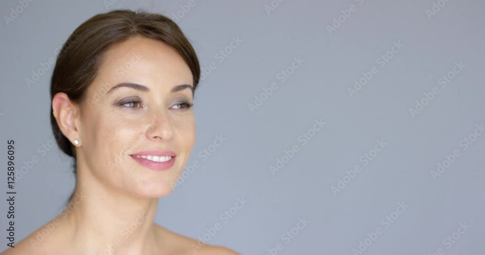 Gorgeous smiling young woman in wrapped up brown hair over gray background with copy space Gorgeous smiling young woman in wrapped up brown hair over gray background with copy space