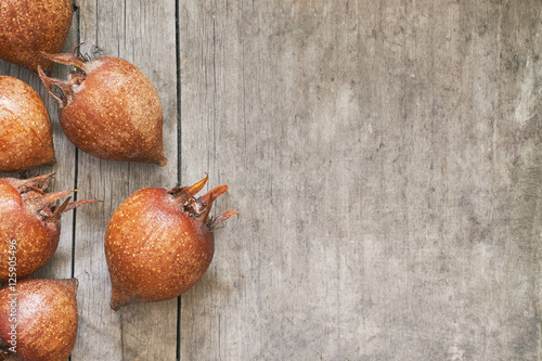 Common medlar fruit (mispel) on grey rustic wooden background. Top view with plenty of copy space