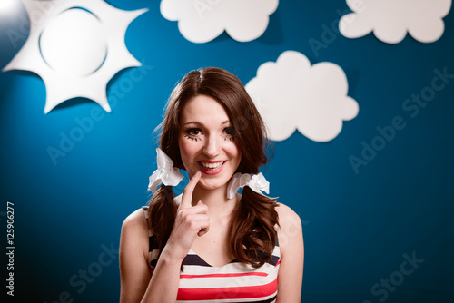 Happy smiling pretty young woman over blue paper sky with white clouds copy space background