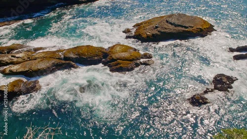 Gliding nature shot of picturesque and mysterious Cape Flattery bay by Pacific ocean coast with rich and colorful blue water, powerful waves and trees on a sunny, warm summer day