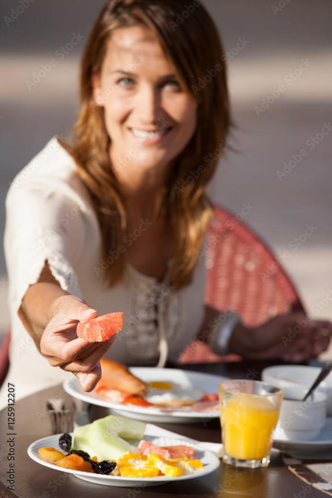 femme souriante qui prend un petit déjeuner en extérieur