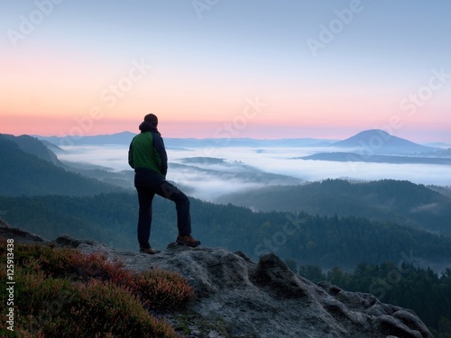 Hiker man on rock watch over creamy mista and foggy morning landscape.