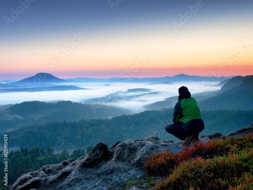 Hiker  man on rock watch over creamy mista and foggy morning landscape.