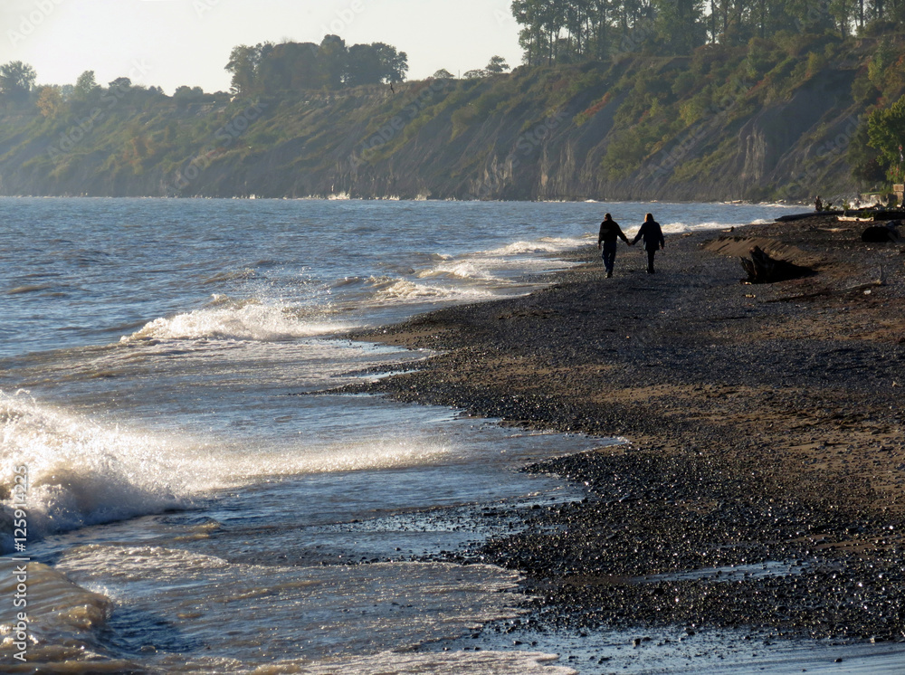 Couple holding hands walking on beach on a misty fall day. Couple holding hands walking on beach on a misty fall day.