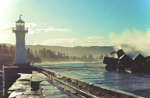 Big waves breaking over Wollongong harbor breakwall and lighthouse, Wollongong, New South Wales, Australia