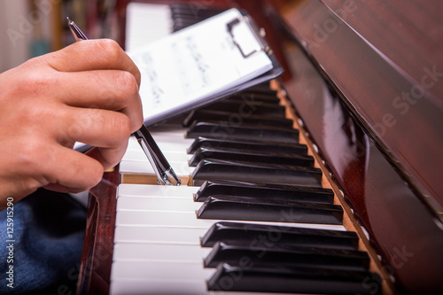 Holding piano song on a clipboard and playing piano with ballpen