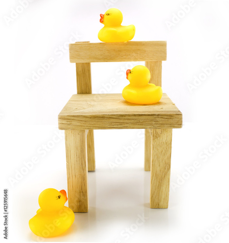 Ducks on a small wooden chair with a white background