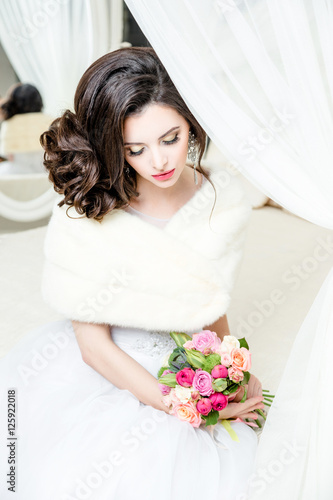 gorgeous bride in luxury wedding dress. Bride. Perfect Make up. Hairstyle, wedding jewelry. Beautiful Woman with Shiny Brown Hair. gorgeous wedding bouquet of various flowers.