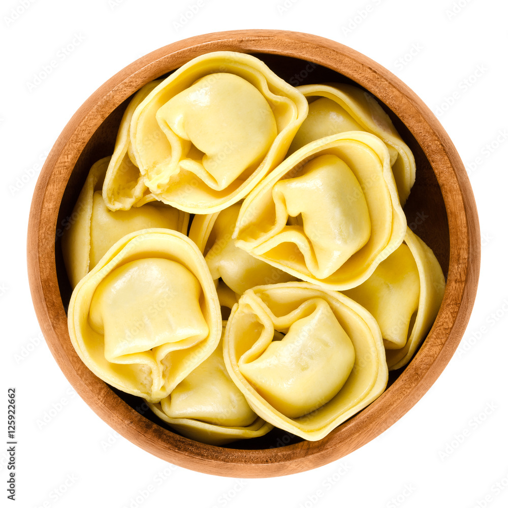 Tortelloni pasta in wooden bowl. Ringshaped stuffed Italian dumplings with same shape as