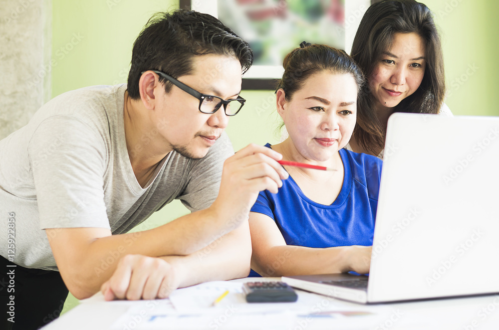 Two women and one man are working with at computer in modern off Two women and one man are working with at computer in modern off