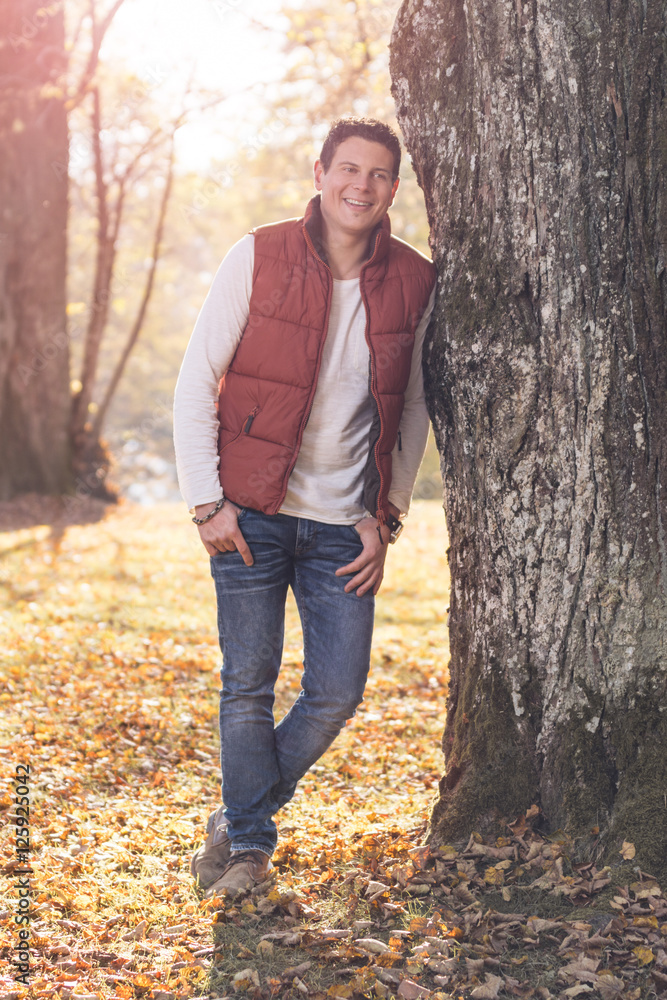 Junger attraktiver Mann, lehnt relaxed an einem alten Baum Junger attraktiver Mann, lehnt relaxed an einem alten Baum